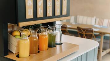 A bar area with wooden shelves displaying various drink options and a wooden counter with glasses of different colored beverages.