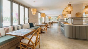 En moderne restaurant med lange fællesspisesteder, polstrede siddepladser og et centralt barområde.
