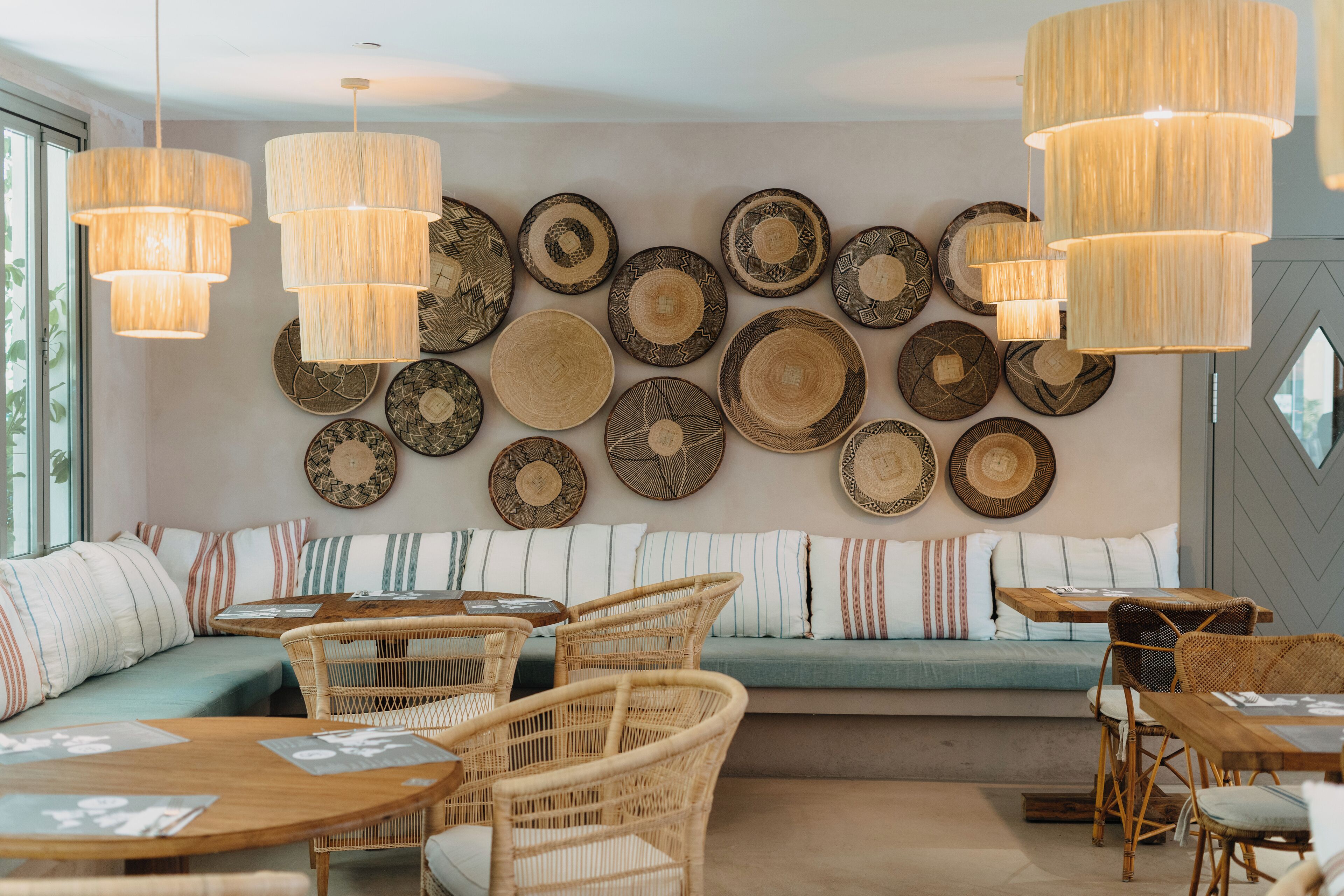 A cozy seating area with wicker furniture, a wall adorned with decorative plates, and pendant lighting.