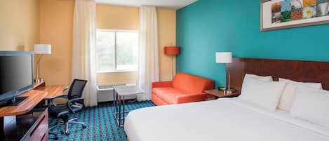 Une chambre d’hôtel comprenant un lit, un bureau avec un ordinateur, une chaise, un canapé et un téléviseur.