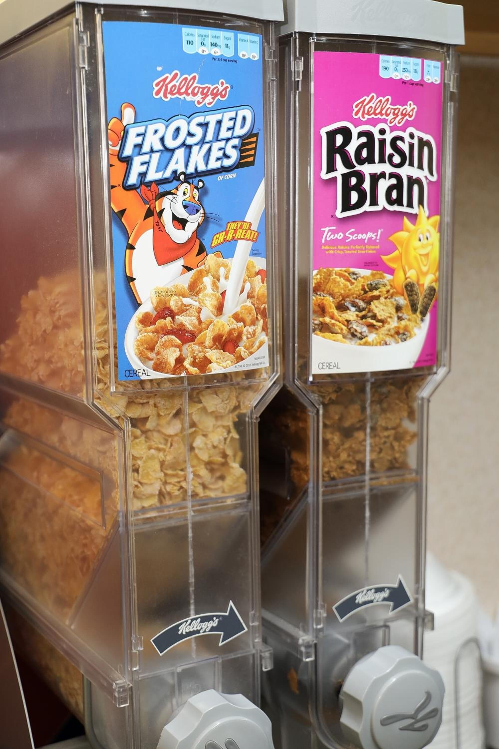 Två spannmålsautomater med etiketter för ”Kellogg’s Frosted Flakes” och ”Kellogg’s Raisin Bran”.