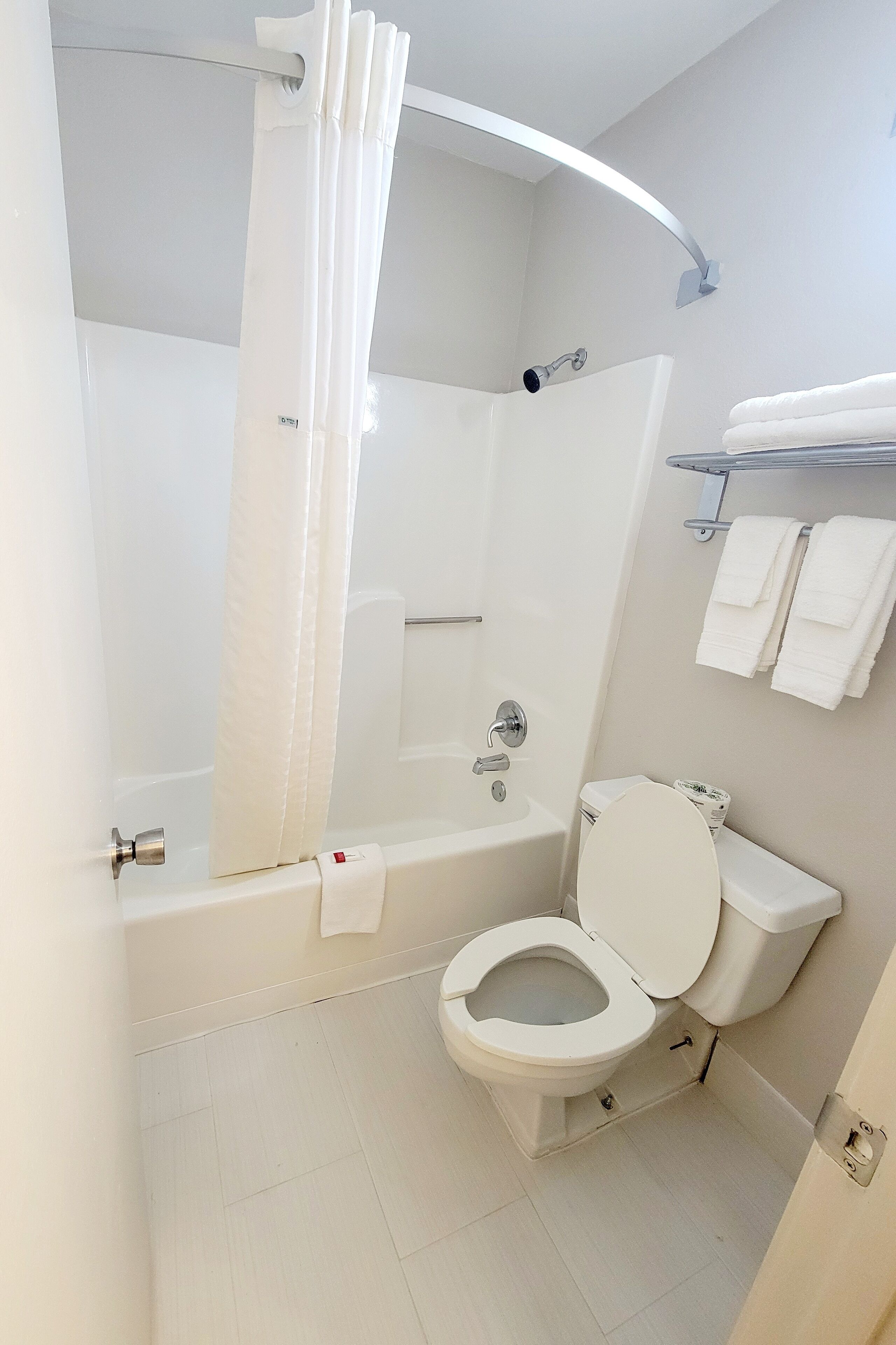 A bathroom with a bathtub, toilet, and shower curtain.