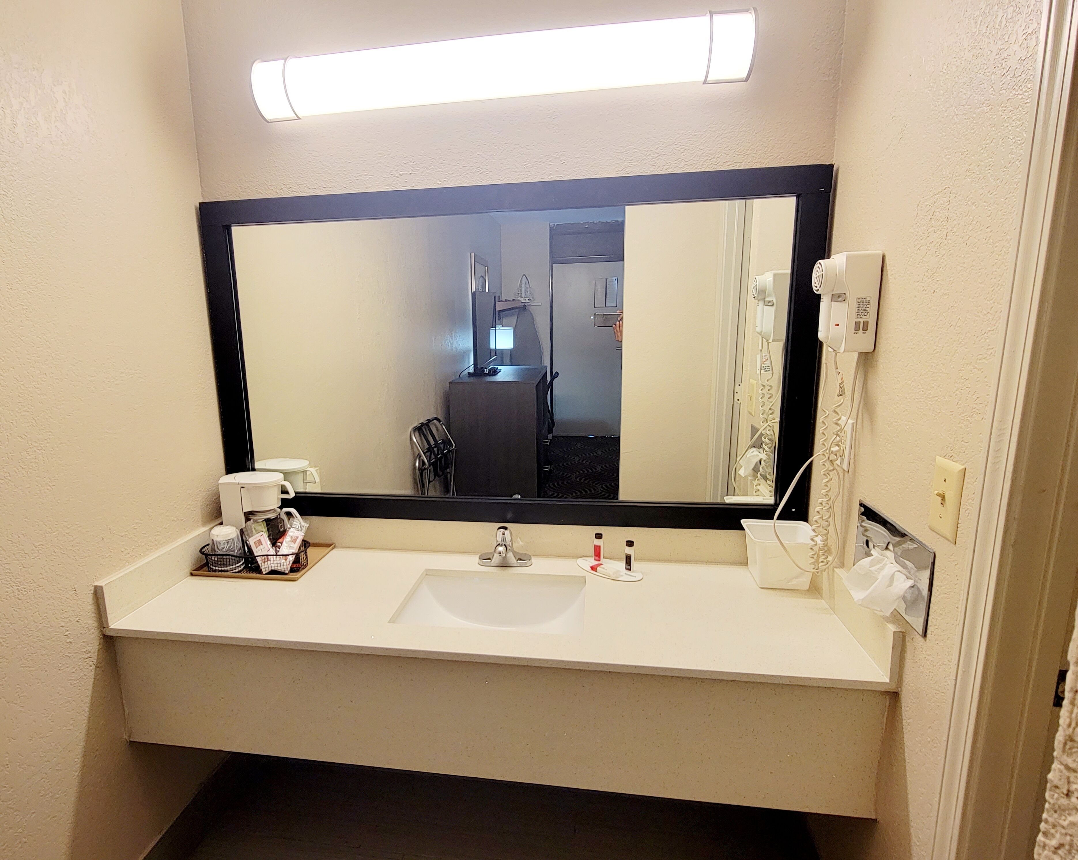 Un baño de hotel con un espejo grande, un lavabo, un secador de pelo y un teléfono.