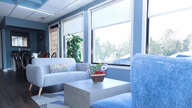 Una sala de estar moderna con un sofá gris, un sillón azul y una mesa de centro con una planta.