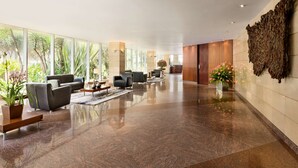 Un vestíbulo espacioso con piso de mármol pulido, asientos modernos, ventanas amplias y una zona de recepción.