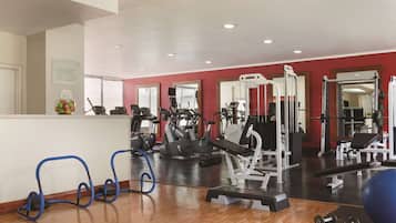 A gym with various exercise equipment, a reception area, and a mirror wall.