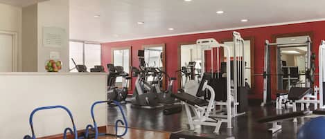 A gym with various exercise equipment, a reception area, and a mirror wall.