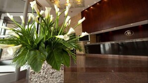 Un área de recepción con un diseño moderno, que incluye un mostrador de mármol y un gran arreglo floral.