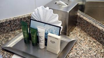 Des articles de toilette sont disposés sur un plateau, notamment un flacon de shampoing, un après-shampoing et un bonnet de douche.