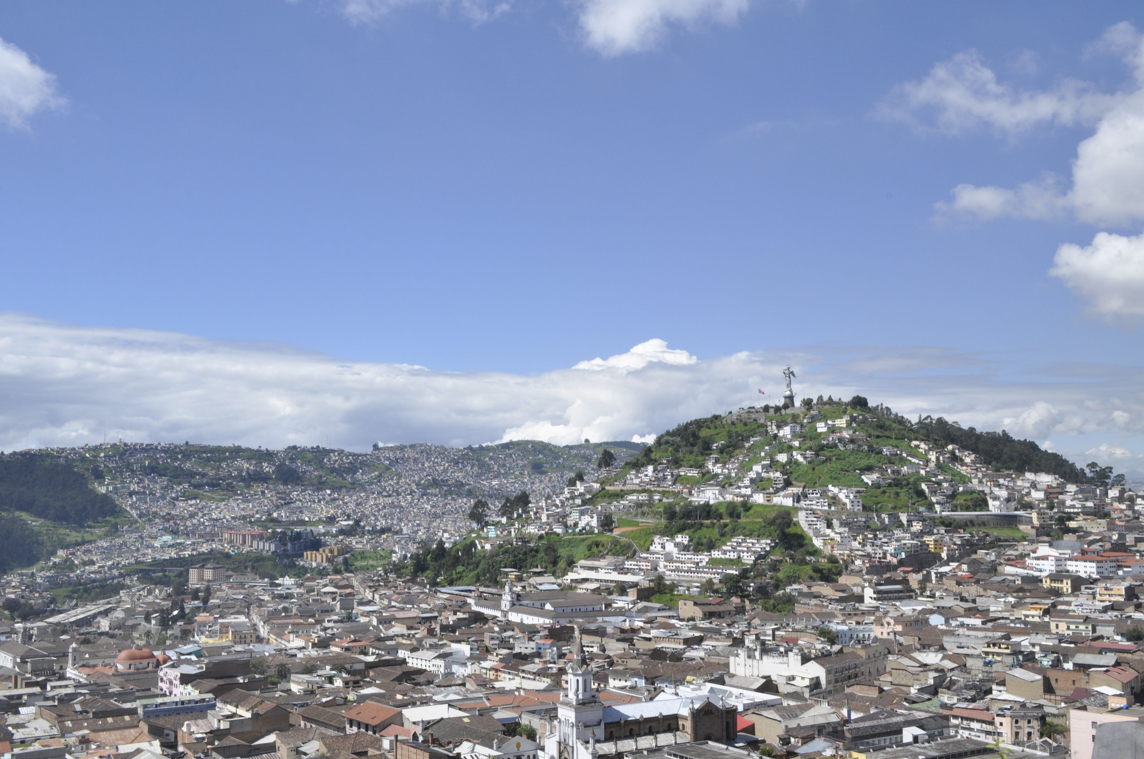 Vista panorámica de una ciudad con una iglesia destacada en la cima de una colina y una zona urbana densa.