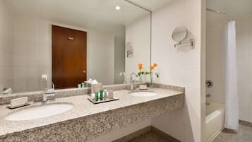 Un bagno con due lavandini, uno specchio grande, una doccia e una porta in legno.