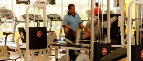 Un gimnasio con máquinas de cardio, equipo de entrenamiento de fuerza y una cinta de correr.