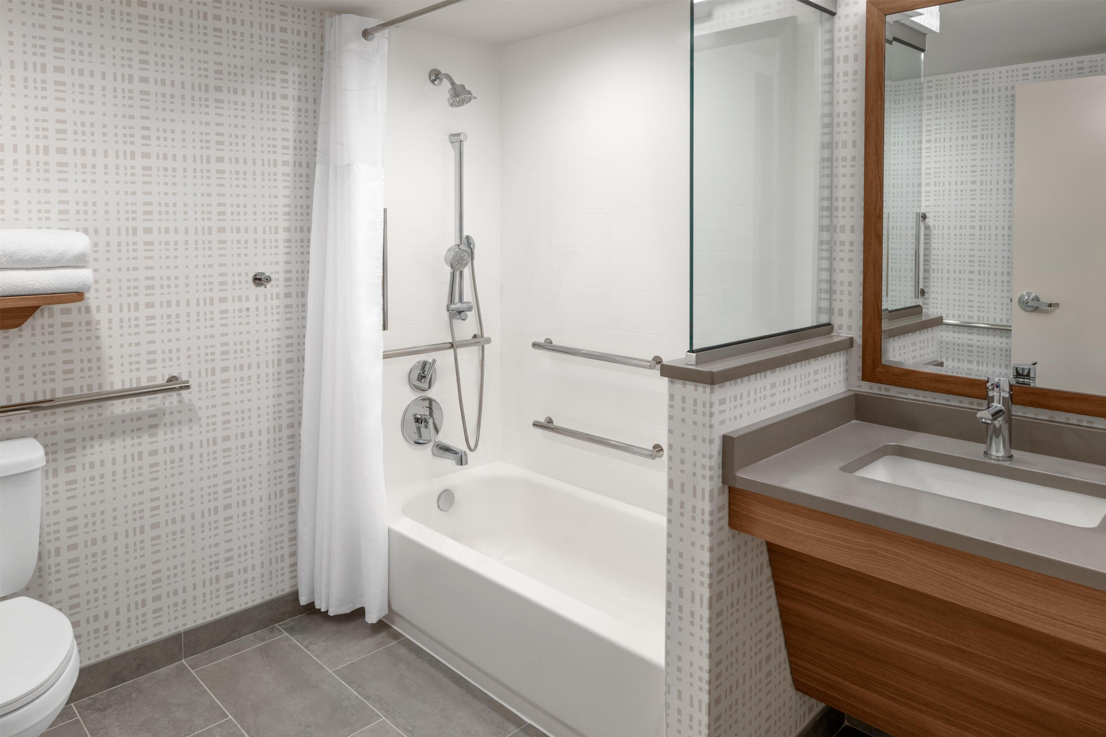 Un baño moderno con bañera, ducha, inodoro y tocador con espejo.