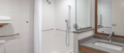 A modern bathroom with a shower, toilet, and sink.