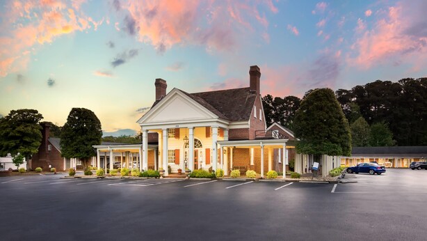 A large, two-story building with a central entrance and a covered porch. - Rodeway Inn Williamsburg Historic Area (Williamsburg)