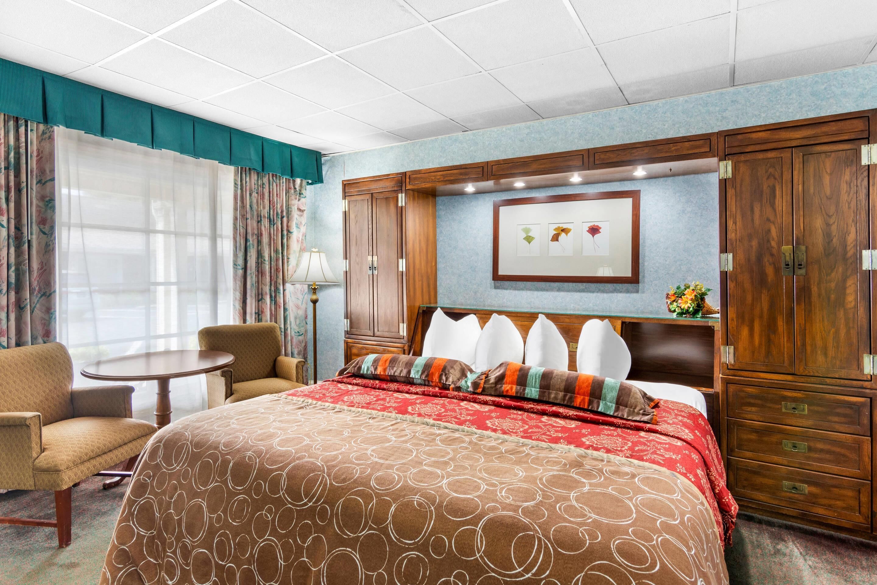 Habitación de hotel con una cama grande, un escritorio, una silla y un armario.