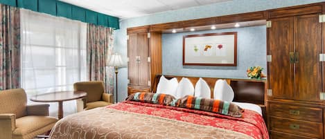 Habitación de hotel con una cama grande, un escritorio, una silla y un armario.