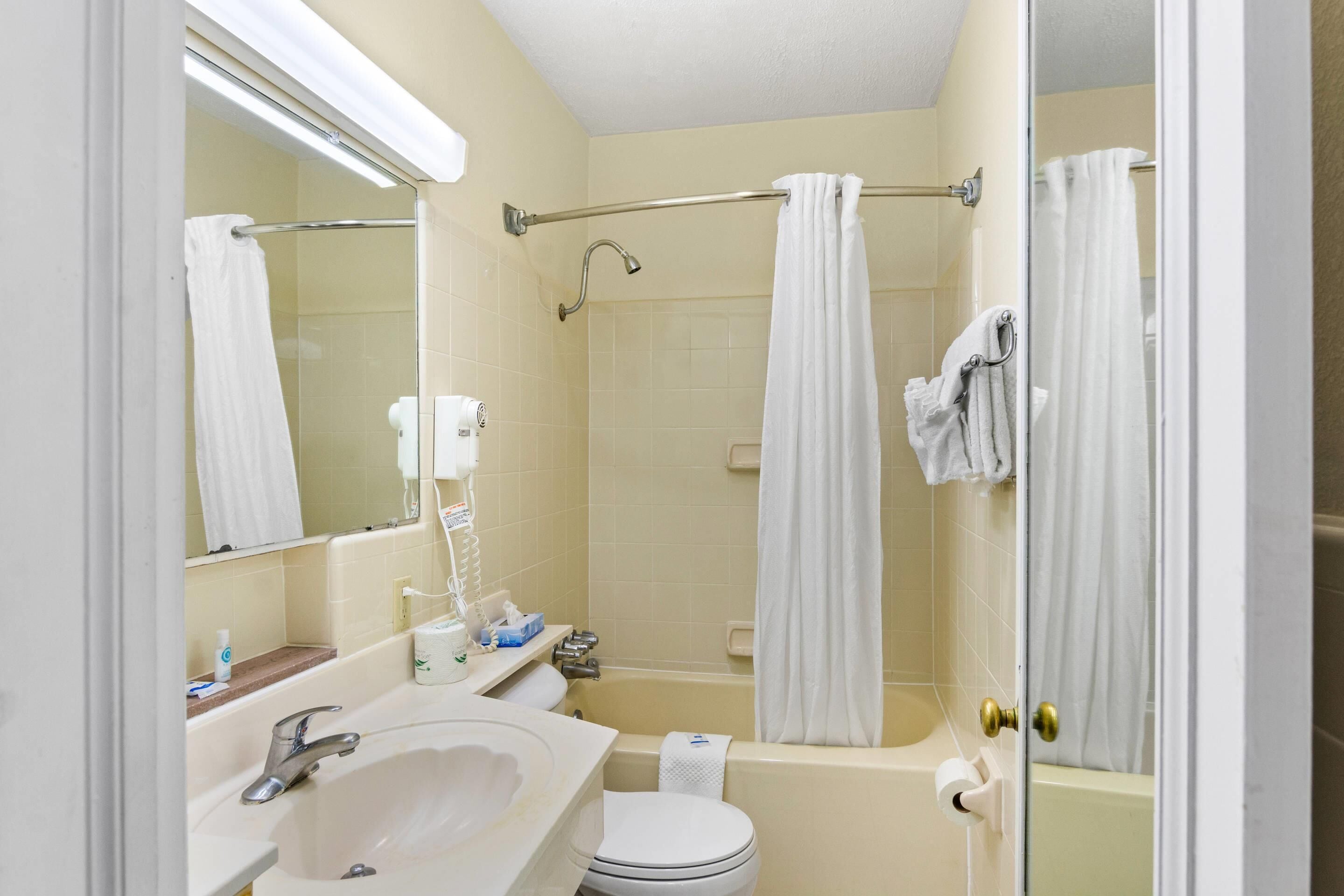 A bathroom with a sink, toilet, bathtub, and shower curtain.
