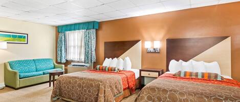 A hotel room with two beds, a sofa, a small table, and a window with curtains.