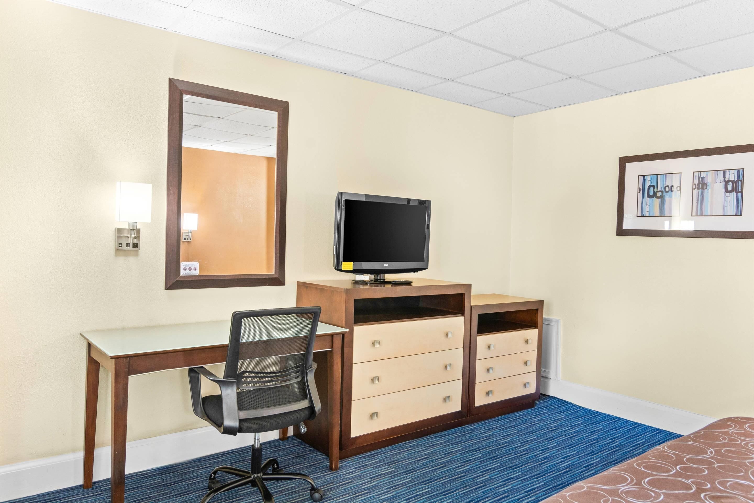 Een hotelkamer met een bureau, stoel, televisie en een bed.