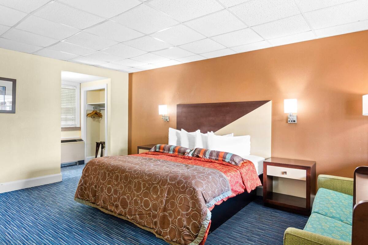 A hotel room with a large bed, a nightstand, a chair, and a closet.