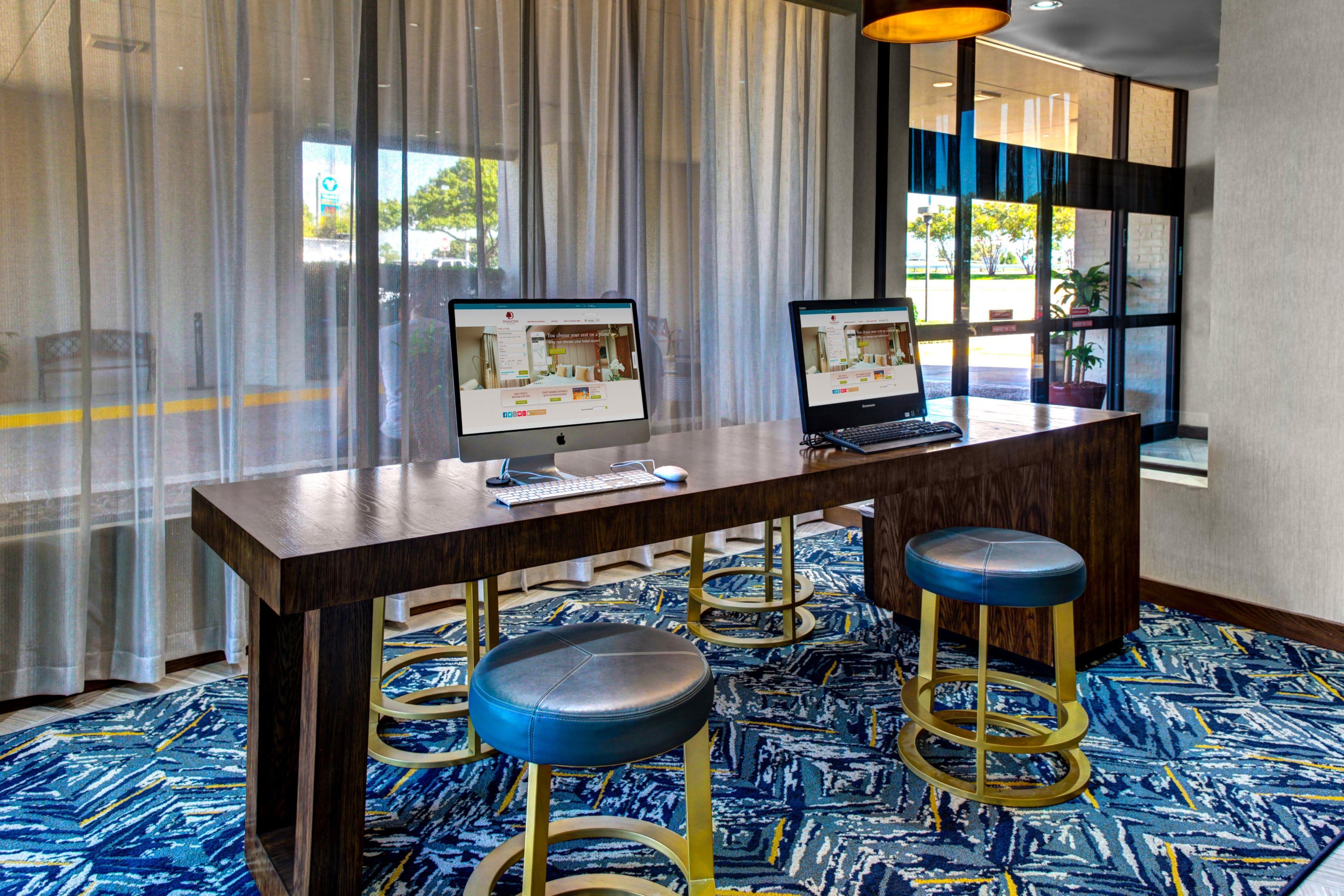 Ein Hotelzimmer mit Schreibtisch, zwei Bildschirmen und einem blau gemusterten Teppich.