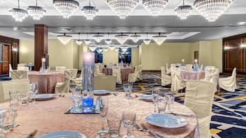 Un salón de banquetes con mesas redondas, sillas y candelabros.