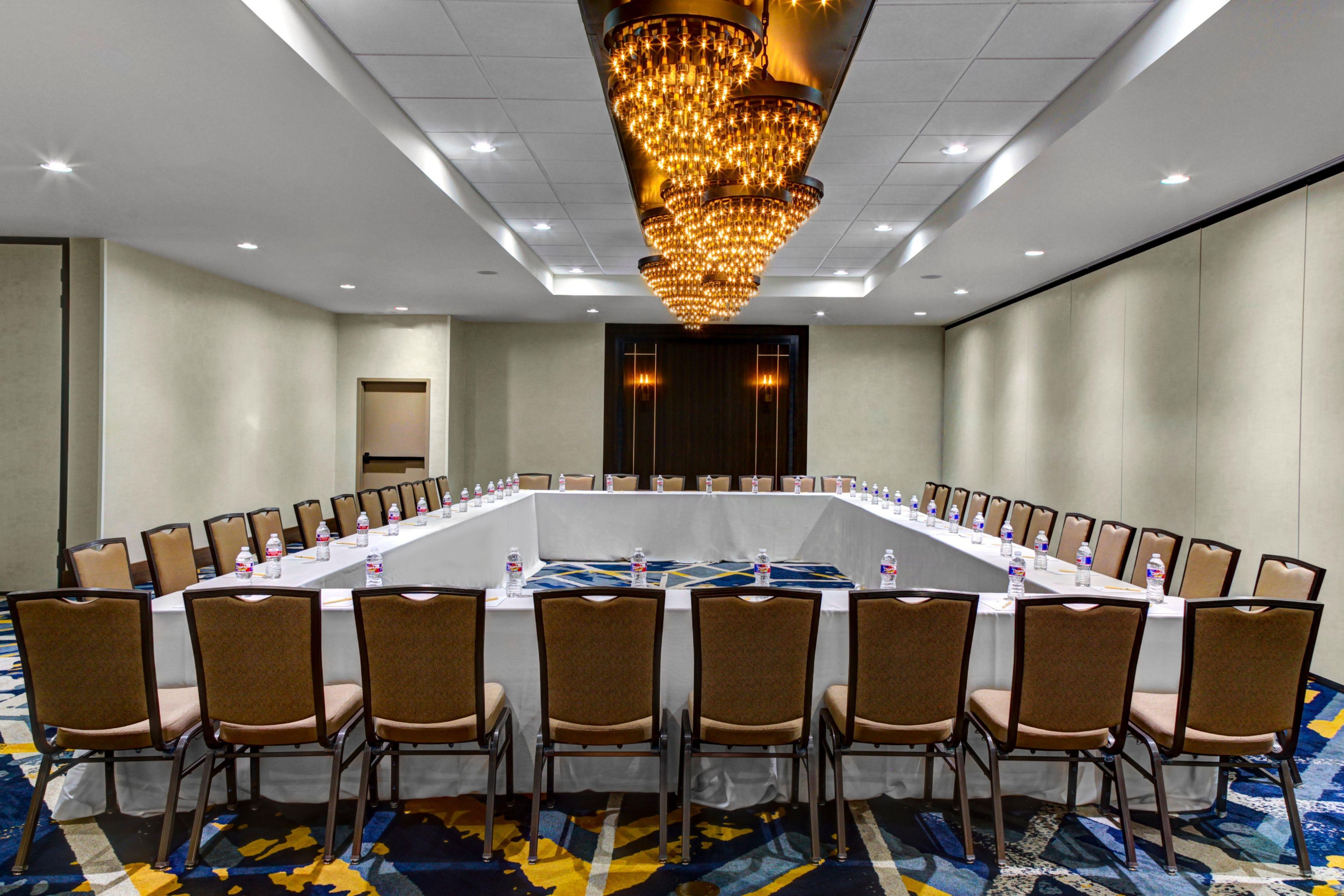 A conference room with a long table, chairs, and a chandelier.