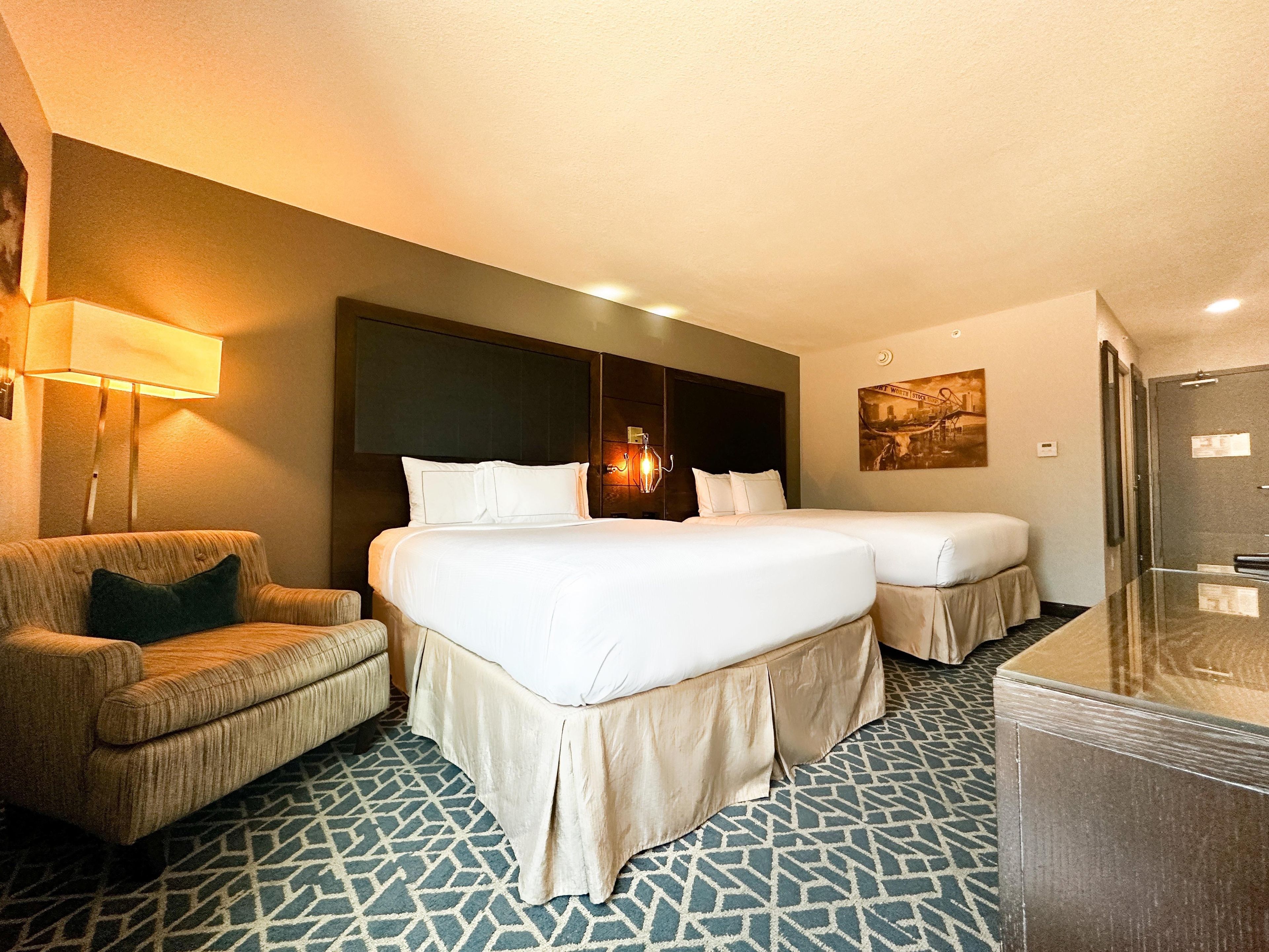 Une chambre d’hôtel avec un grand lit, un lit plus petit, un canapé, un bureau et un miroir.