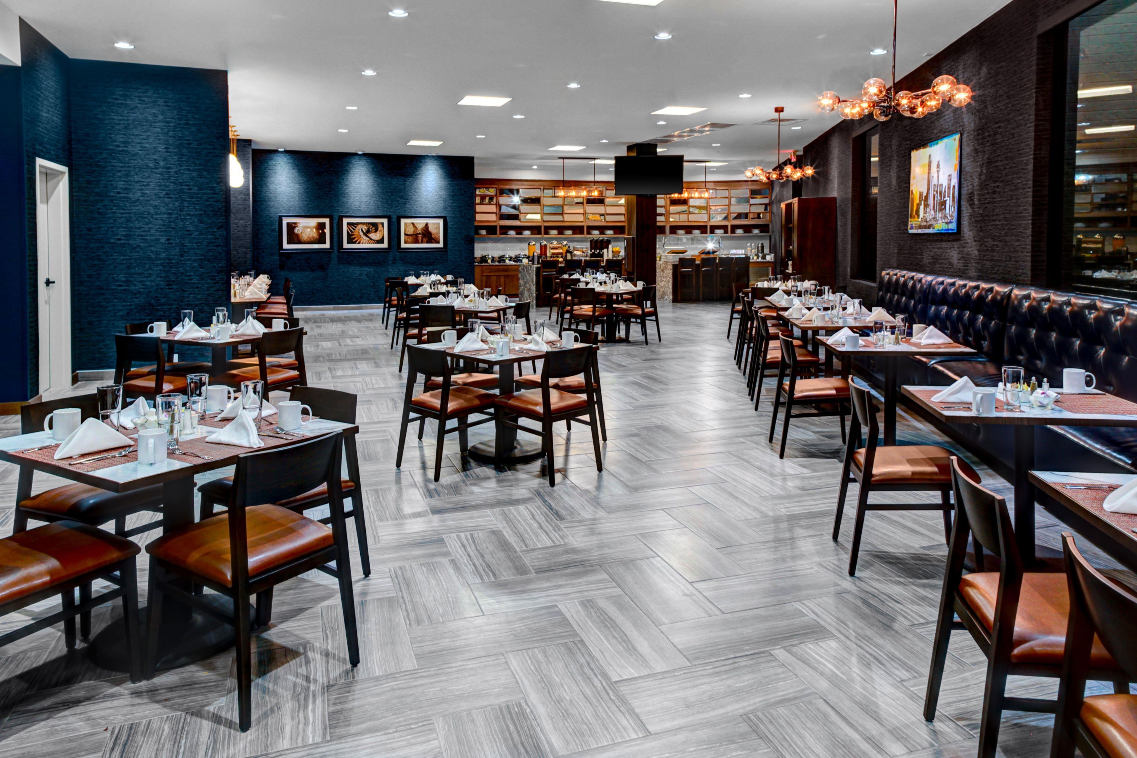 Un restaurant doté de plusieurs tables et chaises, d’un bar et d’un espace détente avec un banc rembourré.