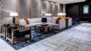A modern hotel lobby with a sectional sofa, armchairs, a coffee table, and a patterned rug. - DoubleTree by Hilton Hotel Arlington DFW South (Arlington)
