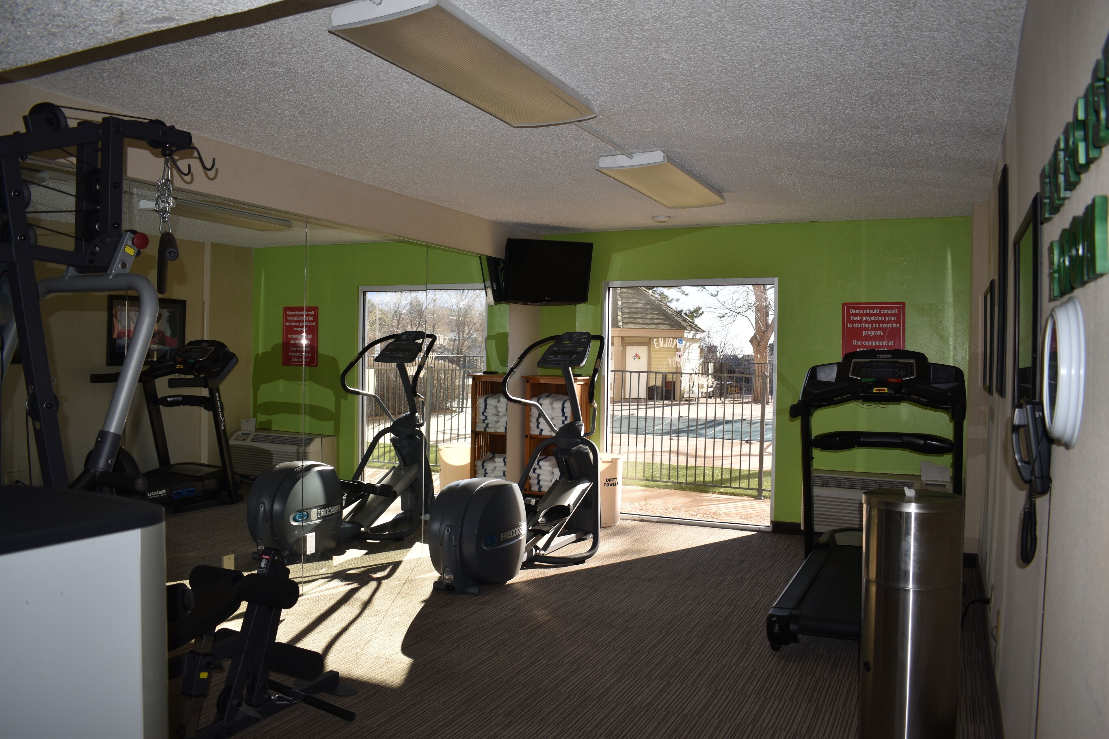 A gym with exercise equipment, a treadmill, and a mirror.