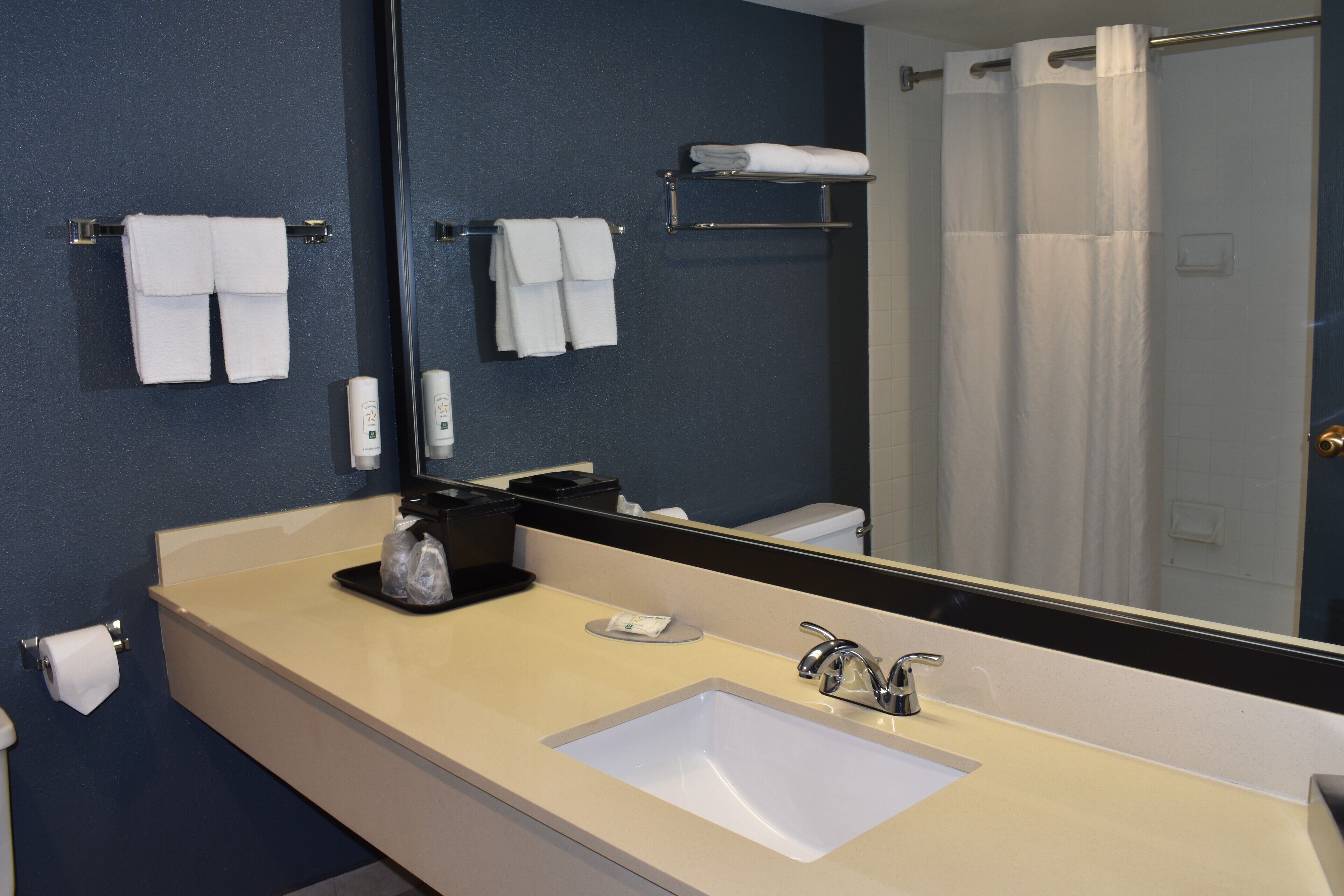 A bathroom with a large mirror, a sink, and towels on a rack.
