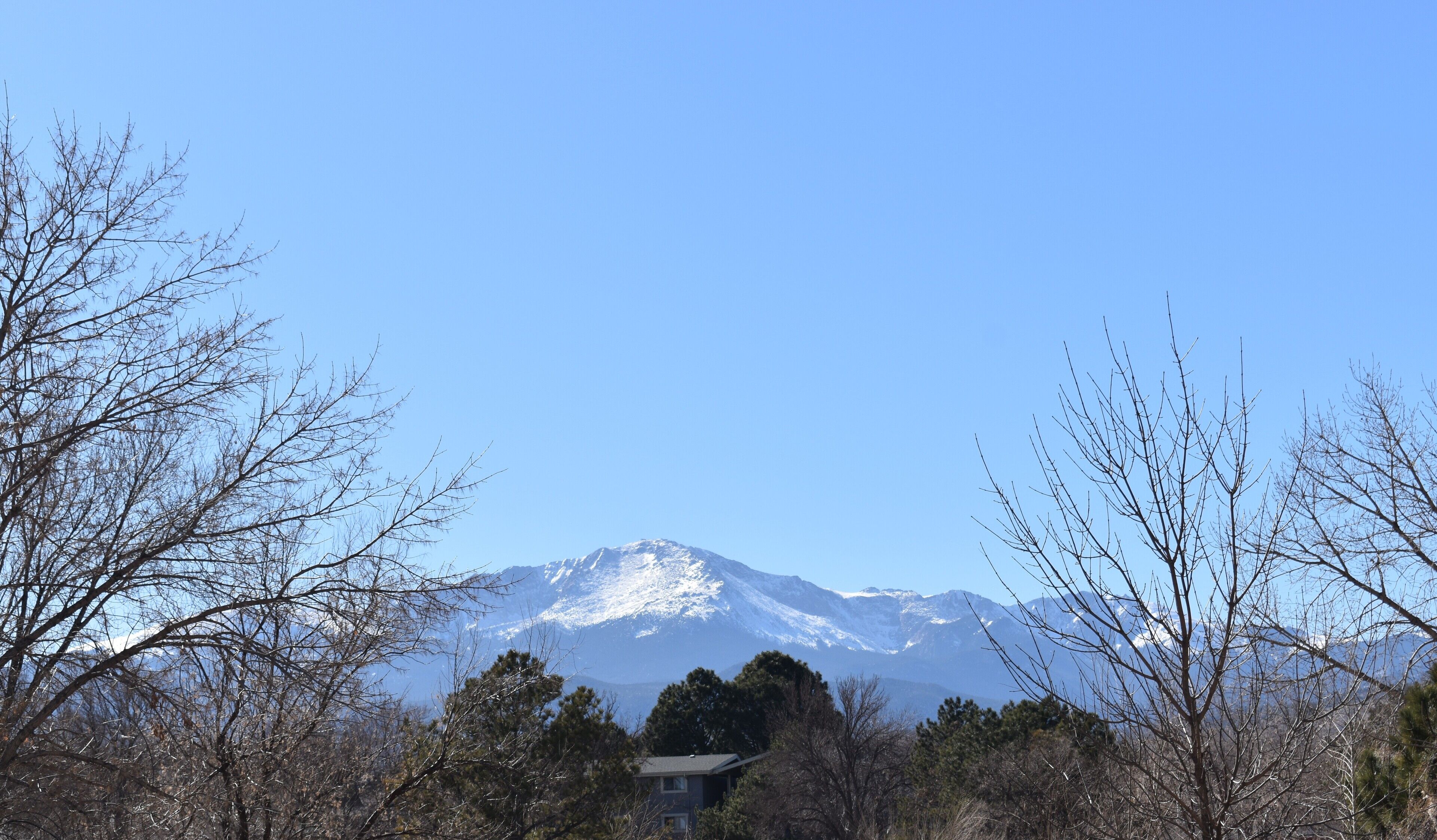 Une montagne dont les sommets enneigés se dressent sous un ciel bleu dégagé.