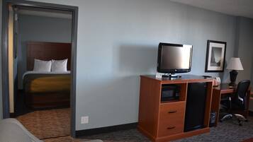 A hotel room with a bed, a desk with a computer, a television, and a chair.