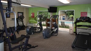 A gym with various exercise equipment, a treadmill, and a view of a pool outside. - Quality Inn and Suites Garden of the Gods (Colorado Springs)