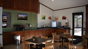 Um restaurante com móveis de madeira, uma área de cozinha e vista pela porta.