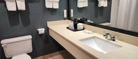 Et badeværelse med et hvidt toilet, en beige vask og et stort spejl.