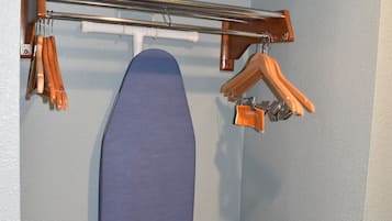 Habitación de hotel con una tabla de planchar azul, un perchero y un planchador fijado al techo.