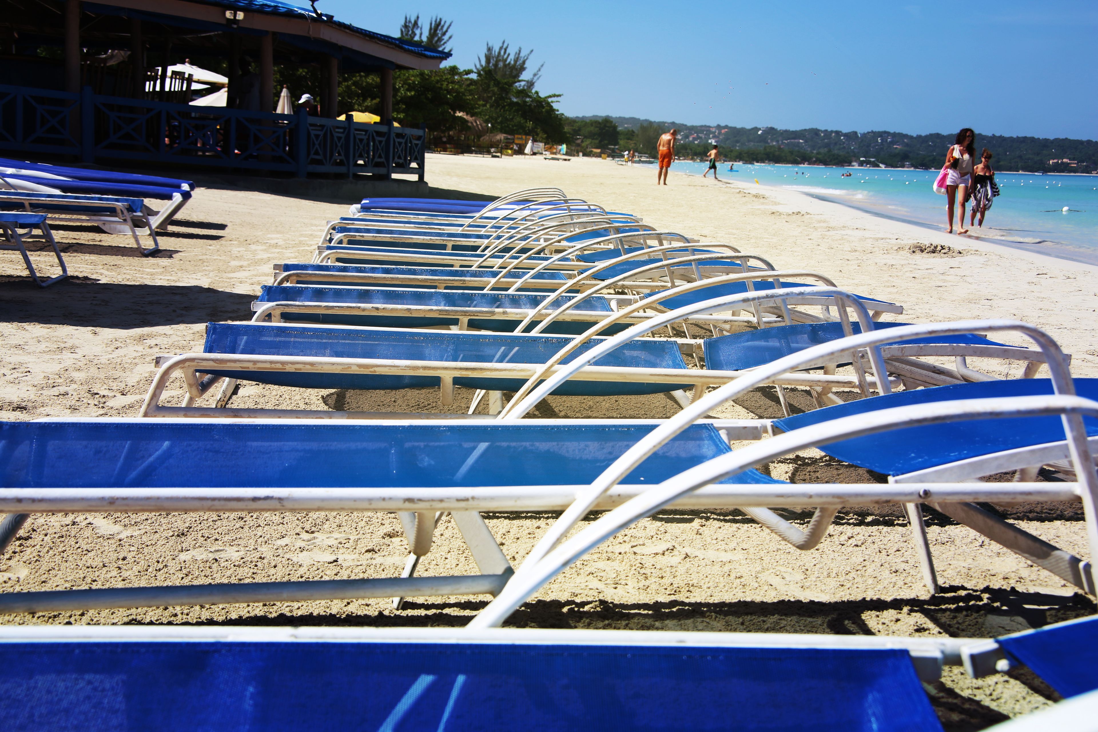 Filas de sillas de playa azules alineadas en una playa arenosa.