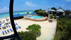 A resort with a pool, beach area, and lounge chairs.