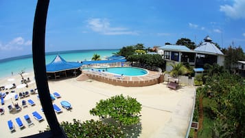 Ein Resort mit Pool, Strandbereich und Liegestühlen.