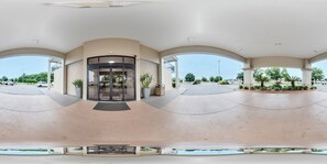 A spacious entrance with a curved glass door, a covered waiting area, and a view of the parking lot.