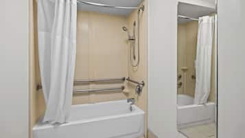 A bathroom with a bathtub, a shower, and a handrail.