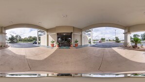 A spacious covered parking area with a central entrance, potted plants, and a clear view of the parking lot. - Quality Inn at Albany Mall (Albany)