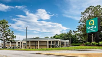 A Quality Inn by Choice Hotels with a two-story building, a parking lot, and a clear sky.