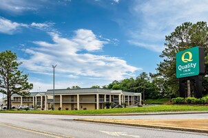 A Quality Inn by Choice Hotels with a two-story building, a parking lot, and a clear sky.