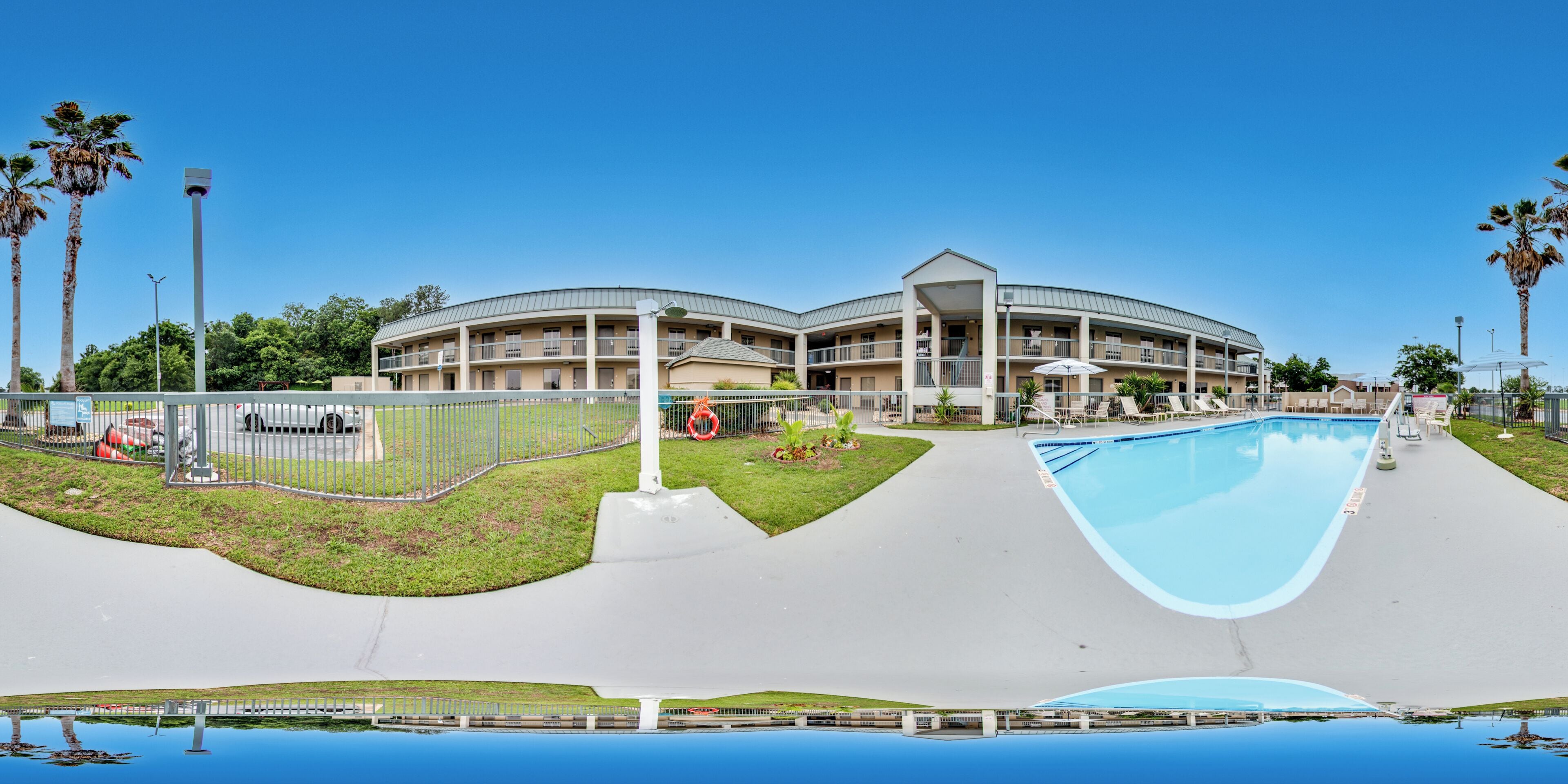 Un hotel de varios pisos con piscina, mobiliario exterior y palmeras.