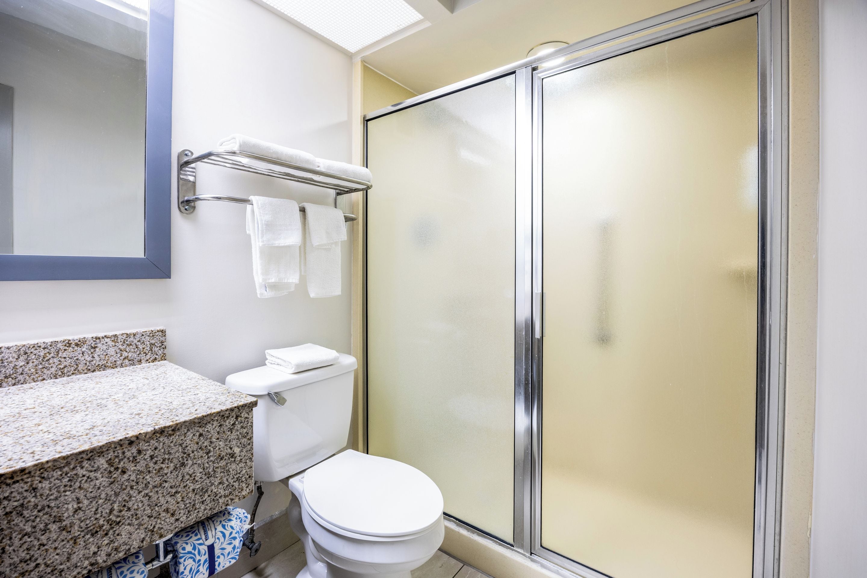 A bathroom with a toilet, a shower enclosure, and a towel rack with towels.