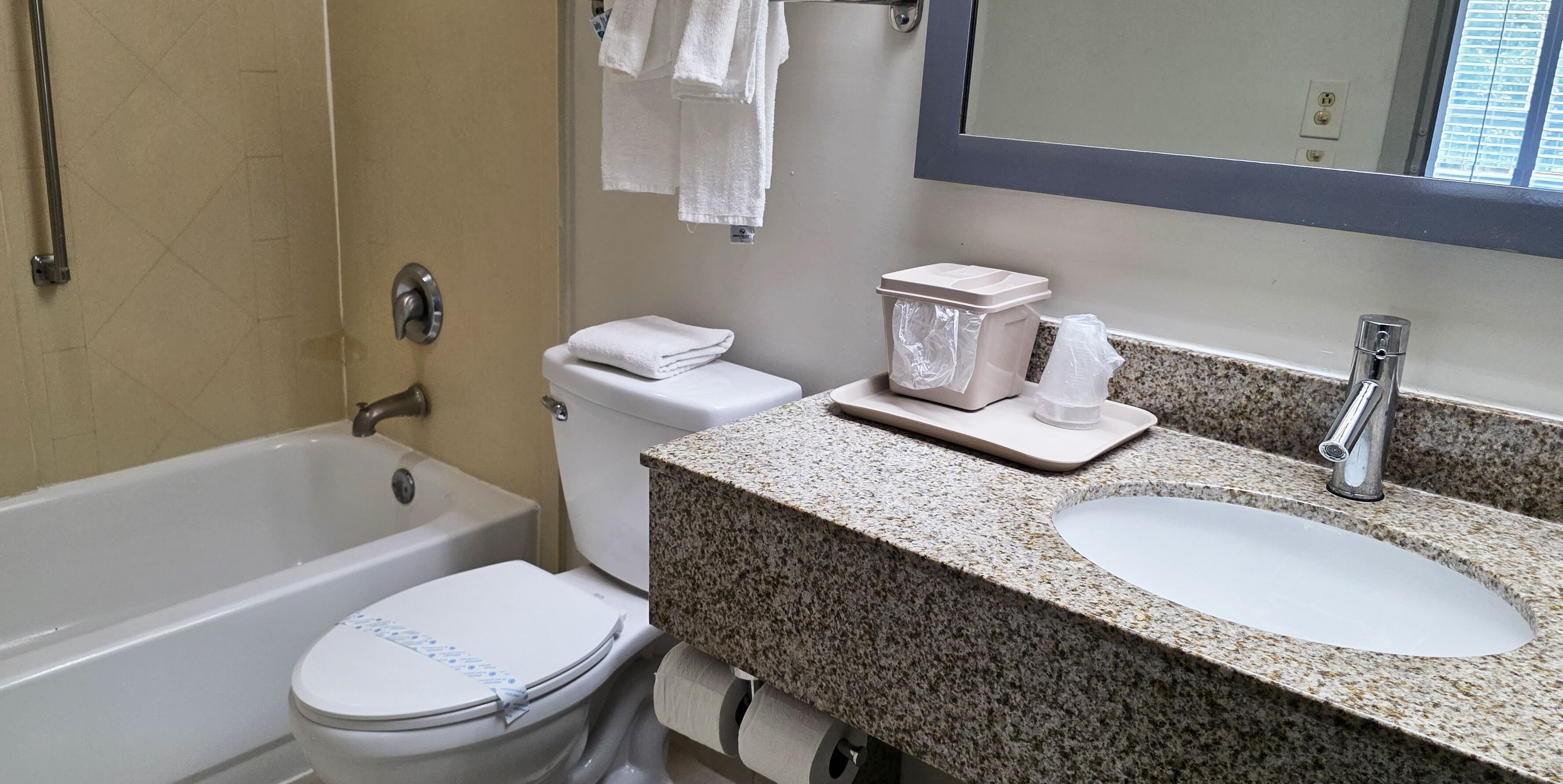 A bathroom with a bathtub, toilet, sink, and a mirror above the sink.